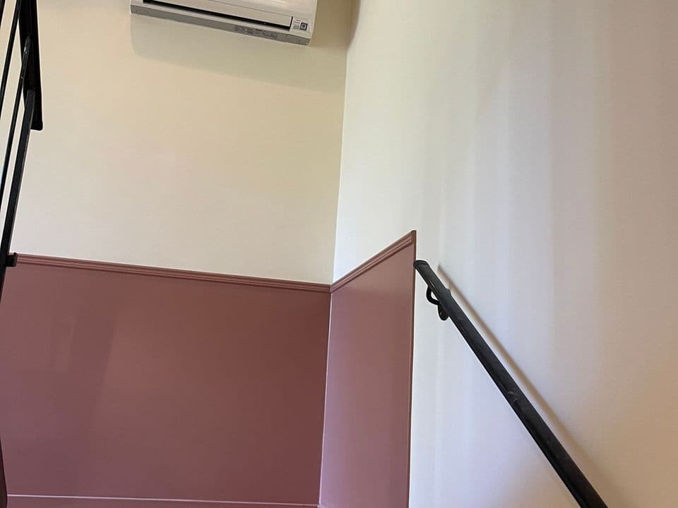 Trappa i ett hem med mörkrosa nederdel och ljus vägg ovanför, målad av GD Måleri