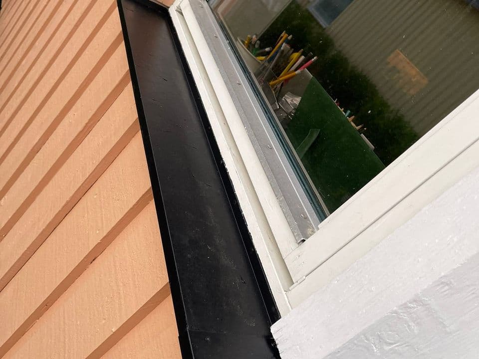 Närbild på vitmålad fönsterbåge och svart fönsterbleck mot panel