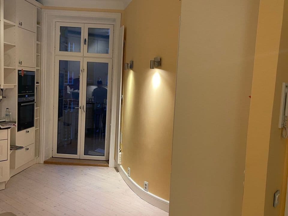 Hall i varmgul kulör med vita snickerier och balkongdörr